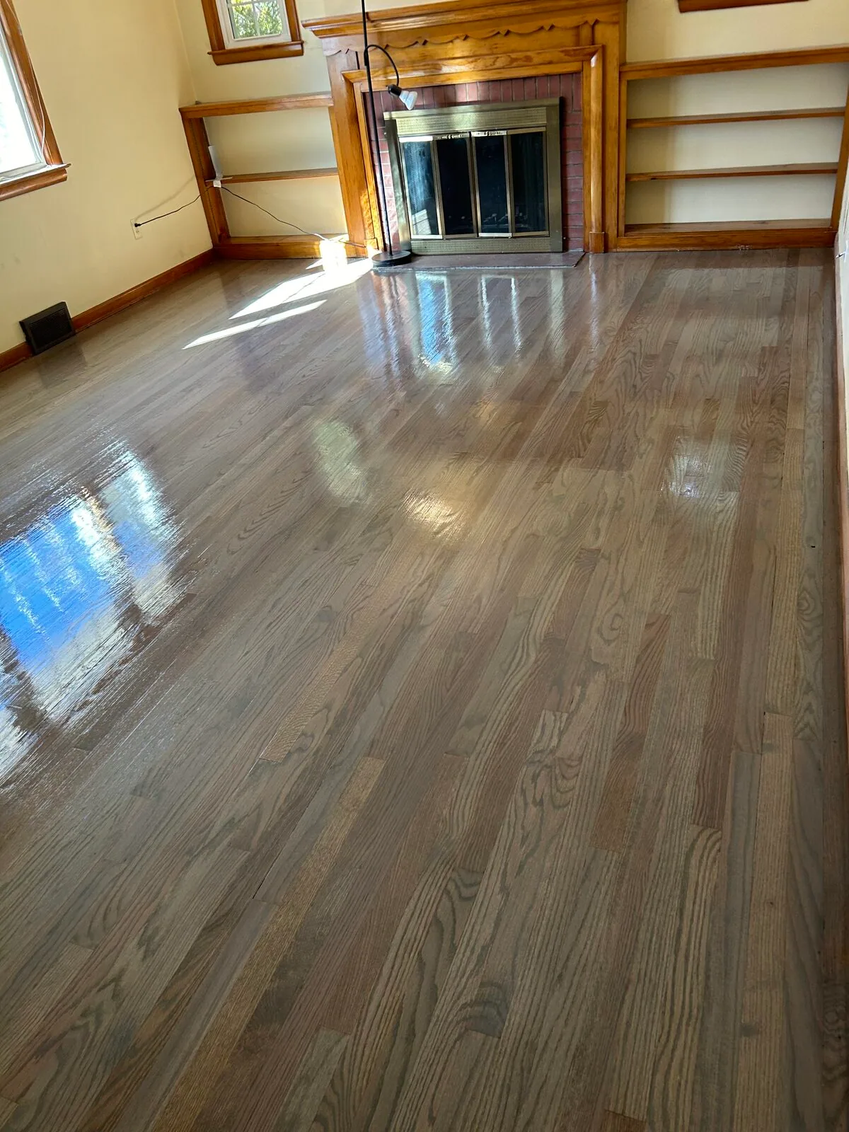 Gray stain refinish in a family room with a brick fireplace and built-in shelves