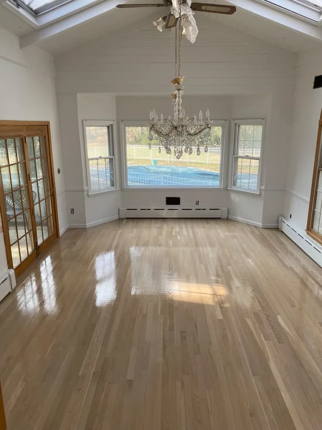 Light natural oak refinish in a dining room with a chandelier and bay window