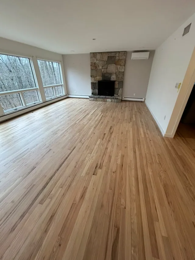 New natural oak floor in a bright room with a stone fireplace